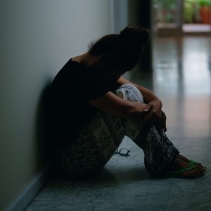 Middle age hispanic woman suffering for domestic violence with bruise on eyes sitting on floor at home